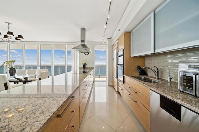 kitchen featuring a water view, backsplash, rail lighting, fume extractor, and light stone countertops