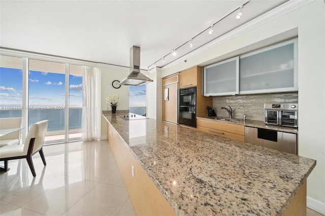 kitchen with tasteful backsplash, a water view, island range hood, black double oven, and rail lighting