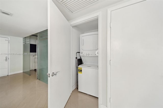 laundry area with stacked washer / dryer and light tile flooring