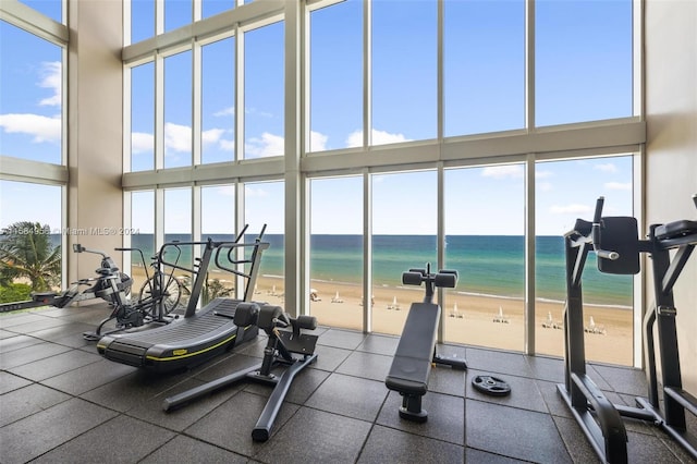 workout area with a healthy amount of sunlight, a beach view, and a water view