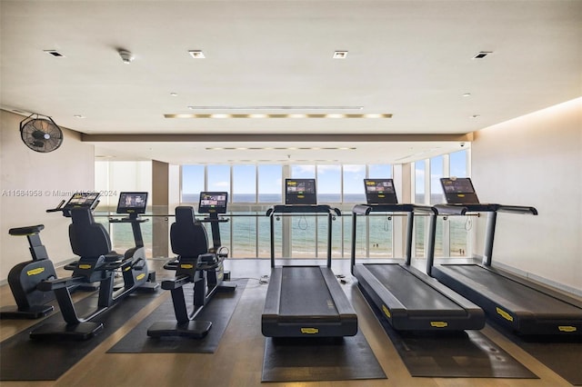 workout area featuring a water view and a wall of windows