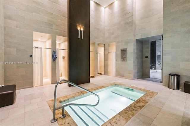 bathroom with tile floors, a towering ceiling, and tile walls