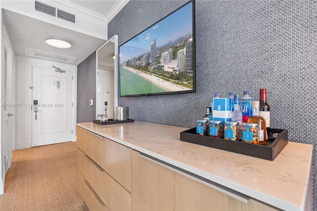 bar with light stone counters, crown molding, and light brown cabinetry