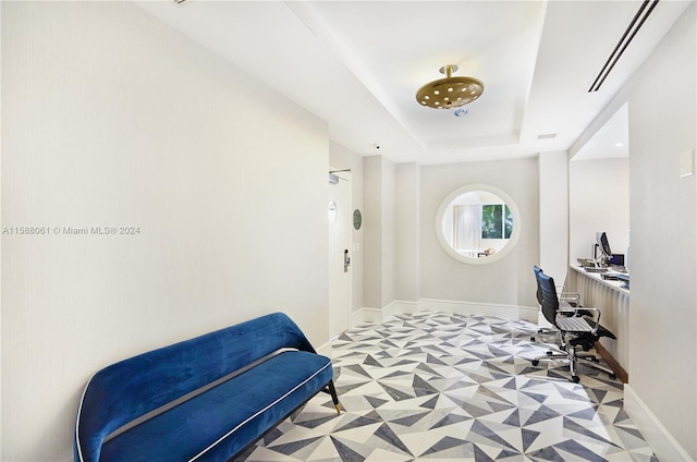 interior space with light tile floors and a raised ceiling