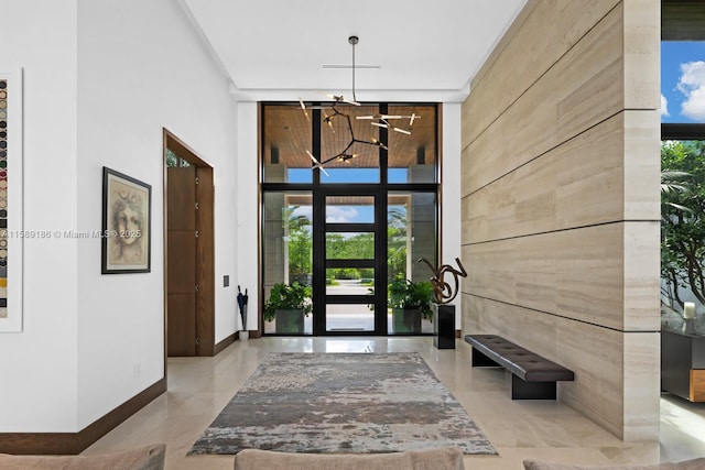 foyer with floor to ceiling windows, plenty of natural light, a towering ceiling, and an inviting chandelier