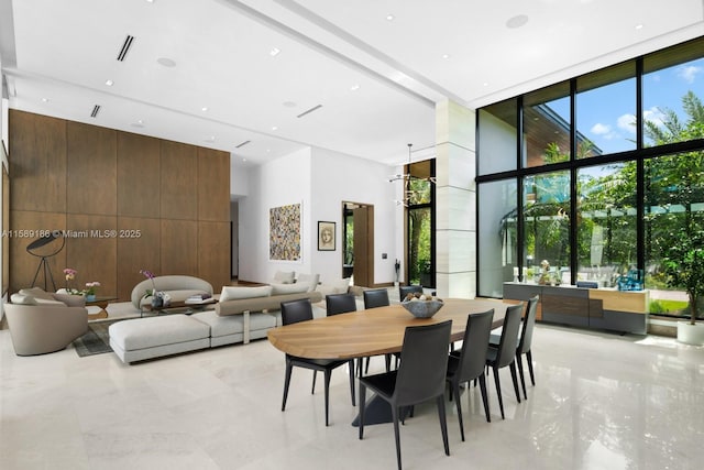 dining area featuring wood walls, a high ceiling, and a wall of windows