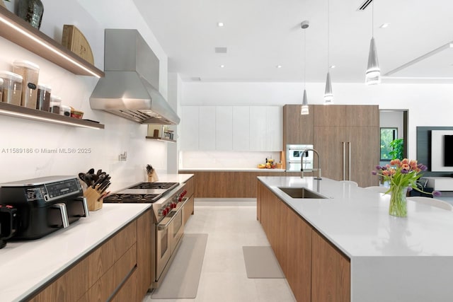 kitchen with pendant lighting, range with two ovens, a spacious island, sink, and wall chimney exhaust hood