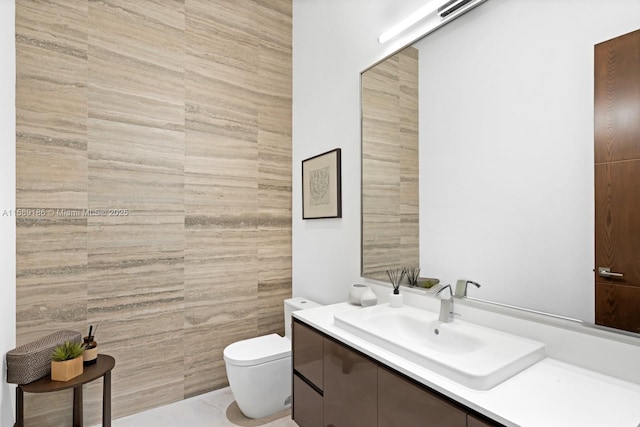 bathroom with tile patterned flooring, vanity, toilet, and tile walls