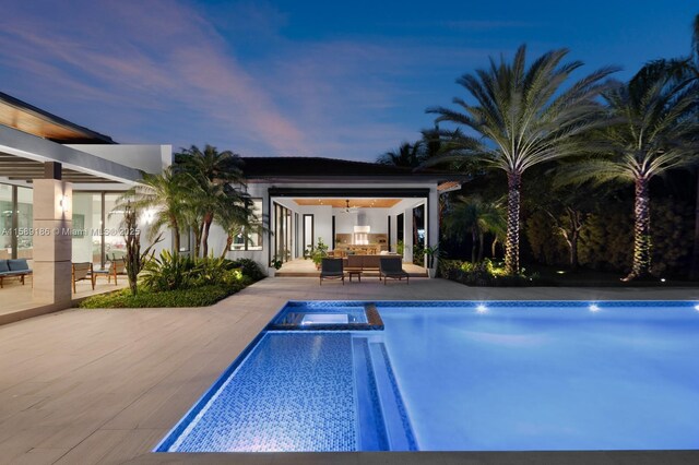 pool at dusk with an in ground hot tub, an outdoor living space, and a patio area