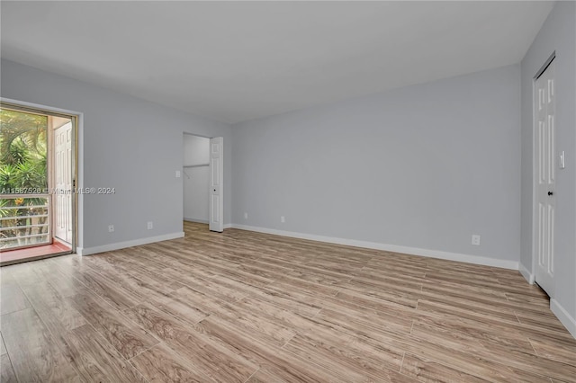 unfurnished bedroom featuring access to outside, a closet, and light hardwood / wood-style floors