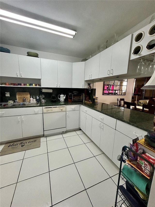 kitchen featuring dark stone counters, white cabinets, light tile flooring, and white dishwasher