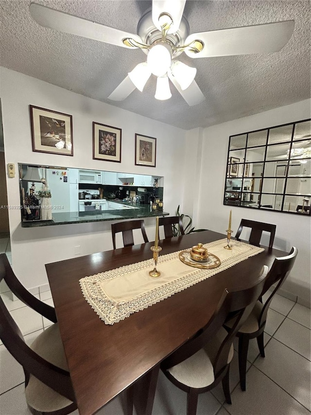 tiled dining area featuring a textured ceiling and ceiling fan