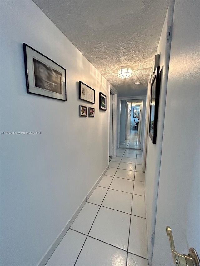 hall with light tile floors and a textured ceiling