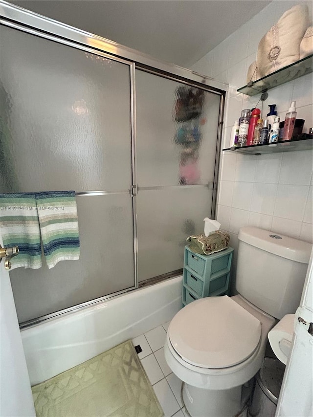 bathroom with tile floors, tile walls, toilet, and enclosed tub / shower combo