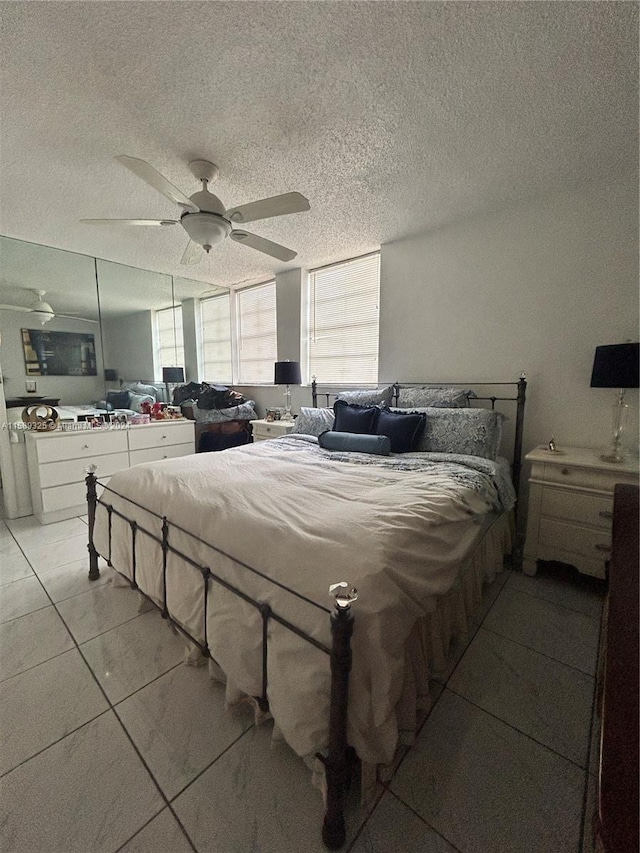 tiled bedroom featuring ceiling fan and a textured ceiling