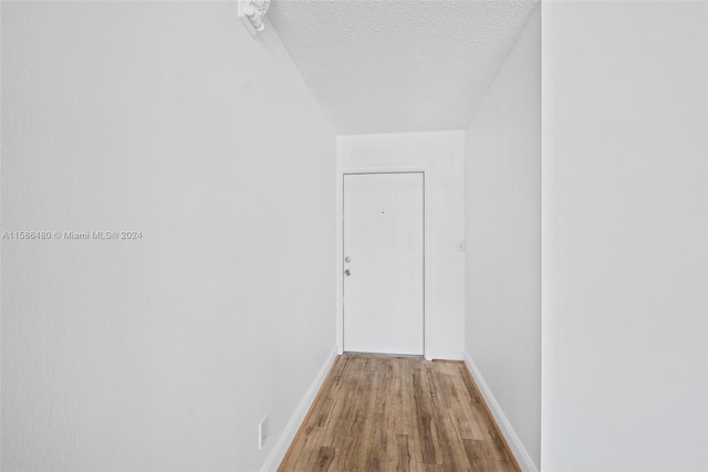 corridor with hardwood / wood-style flooring and a textured ceiling