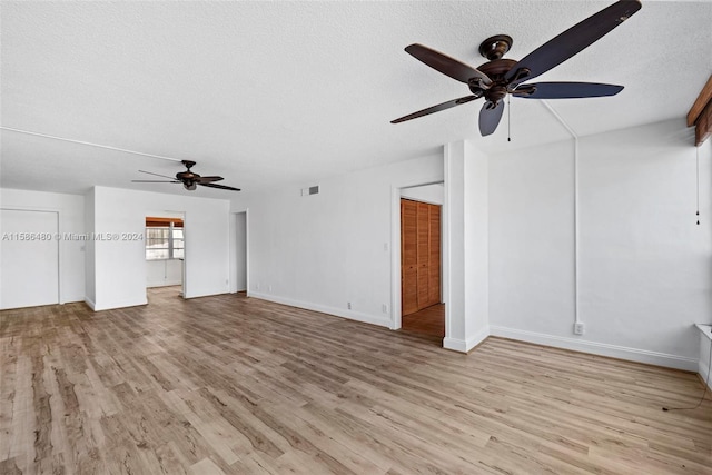 unfurnished living room featuring ceiling fan, light hardwood / wood-style floors, and a textured ceiling