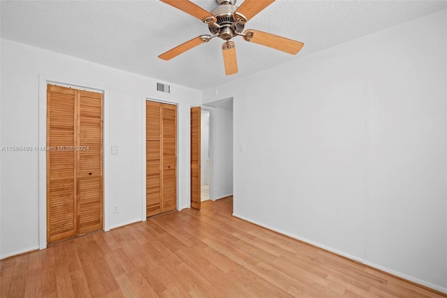 unfurnished bedroom featuring two closets, ceiling fan, and light hardwood / wood-style floors