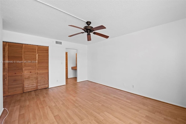 unfurnished bedroom with ceiling fan, a closet, a textured ceiling, and light wood-type flooring