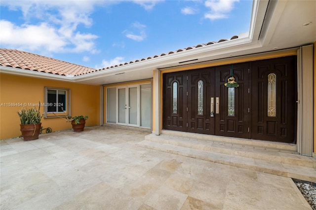 view of exterior entry with a patio area