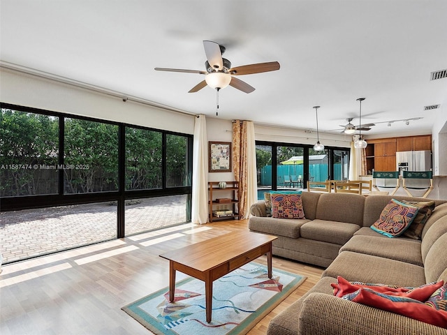 living room with light wood-type flooring, visible vents, and a ceiling fan