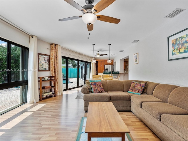 living area featuring a ceiling fan, visible vents, and light wood-style floors