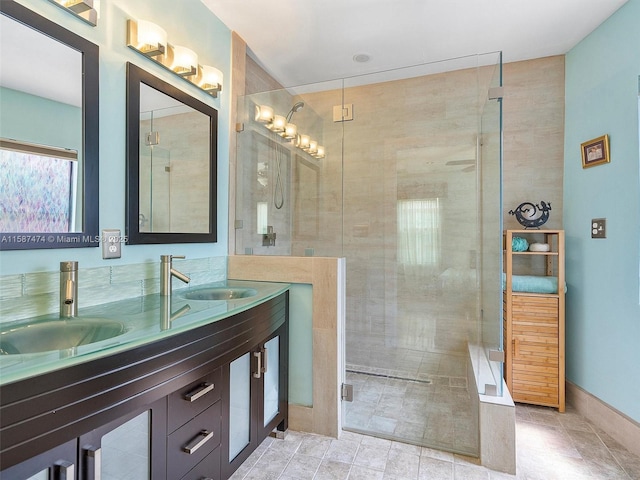 bathroom featuring double vanity, a shower stall, baseboards, and a sink