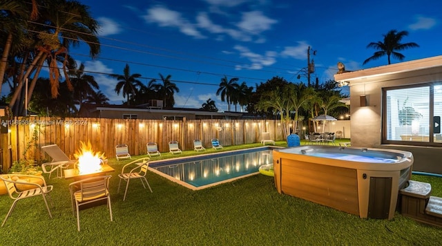 view of swimming pool featuring a yard, an outdoor fire pit, and a hot tub