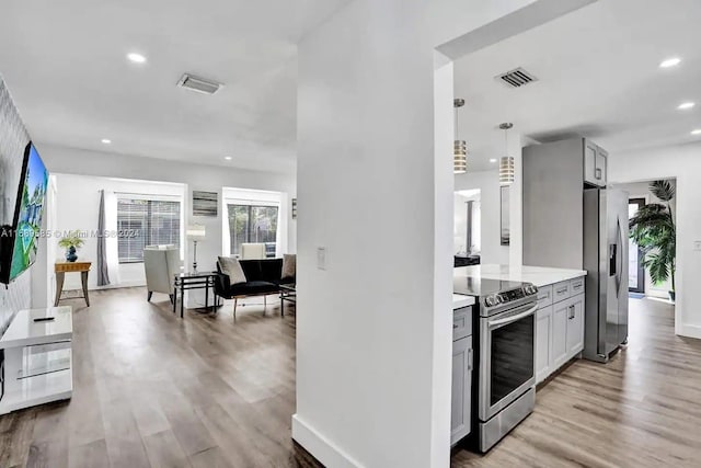 kitchen with pendant lighting, gray cabinetry, light wood-type flooring, and stainless steel appliances