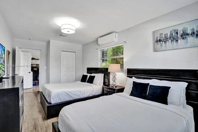 bedroom with light hardwood / wood-style floors and a wall mounted air conditioner