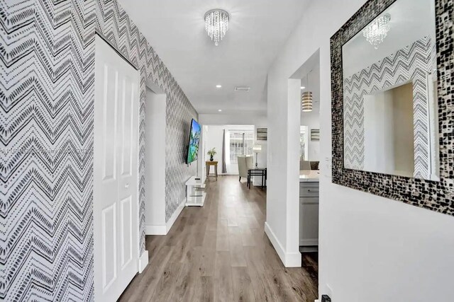 living room with wood-type flooring, baseboard heating, and an inviting chandelier