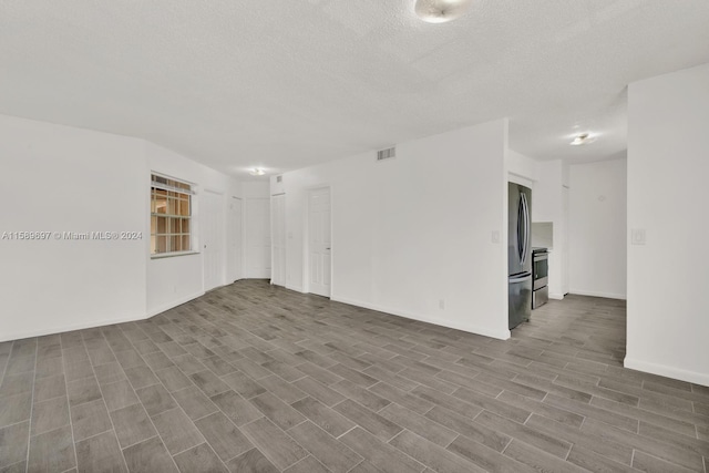 unfurnished room featuring wood-type flooring and a textured ceiling