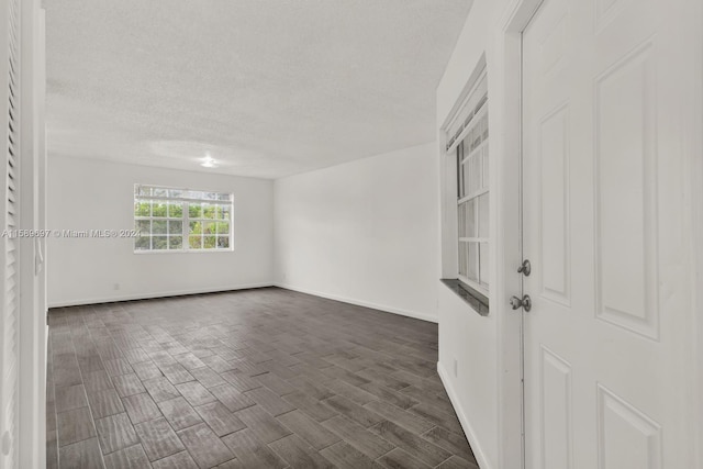 empty room with dark wood-type flooring and a textured ceiling