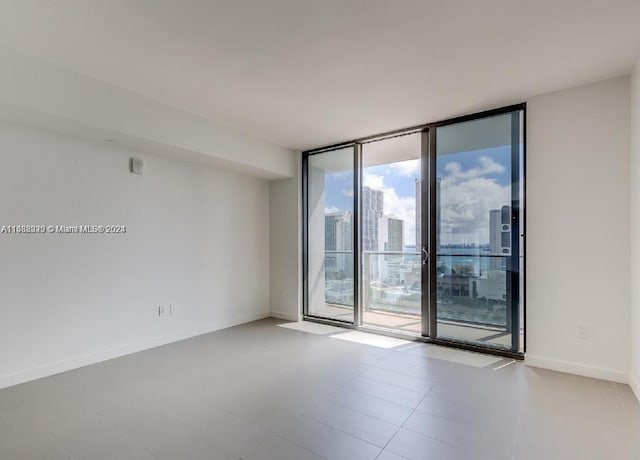 empty room with tile flooring and a wall of windows