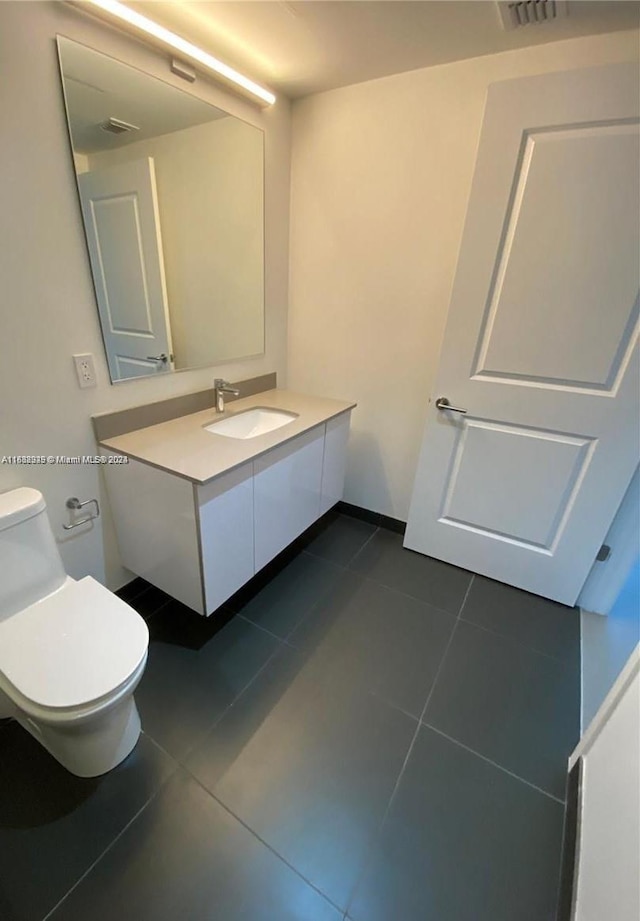 bathroom featuring tile flooring, vanity, and toilet