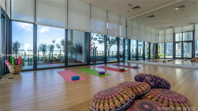 workout area featuring a towering ceiling, expansive windows, and light wood-type flooring