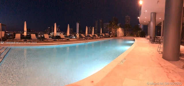 pool at twilight featuring a patio