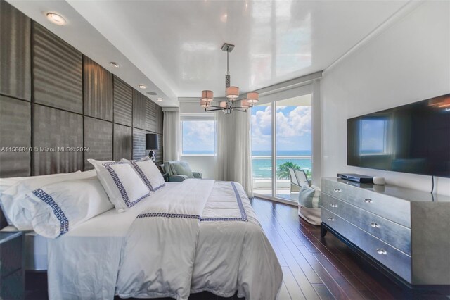 bedroom with dark hardwood / wood-style flooring, a water view, access to outside, and a chandelier