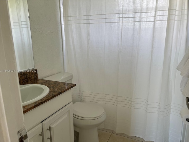 bathroom featuring tile flooring, vanity, and toilet