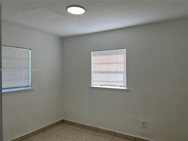 unfurnished room with tile flooring and a textured ceiling