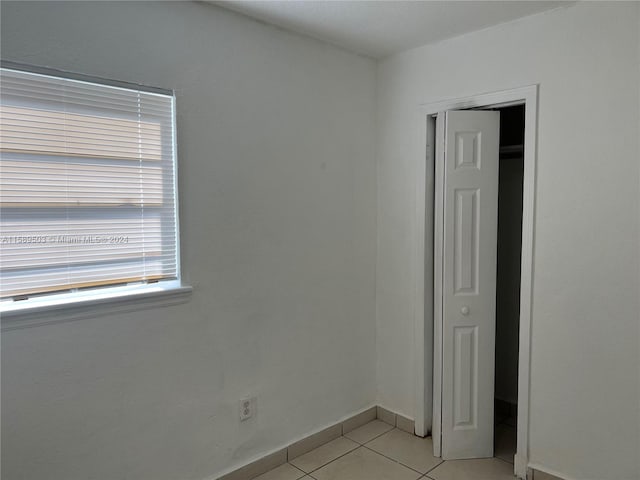 unfurnished bedroom featuring a closet and light tile floors