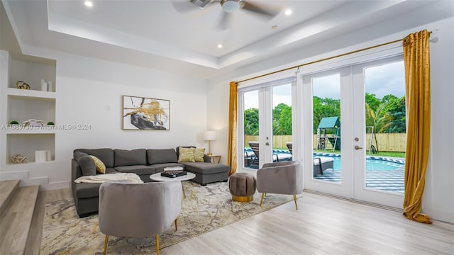 living room with french doors, a tray ceiling, ceiling fan, and light hardwood / wood-style floors