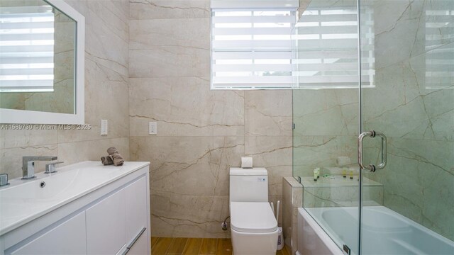 full bathroom featuring vanity, shower / bath combination with glass door, wood-type flooring, washer / clothes dryer, and toilet