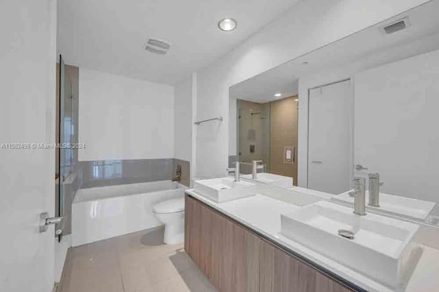 bathroom with tile floors, a bathtub, double vanity, and toilet