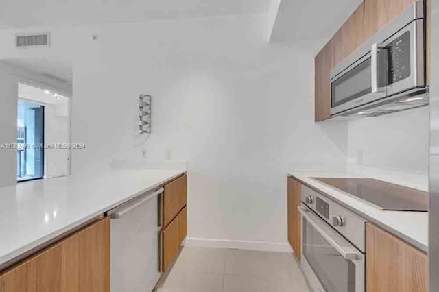 kitchen with stainless steel appliances and light tile floors