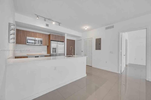 kitchen with stainless steel appliances, light tile floors, sink, and rail lighting