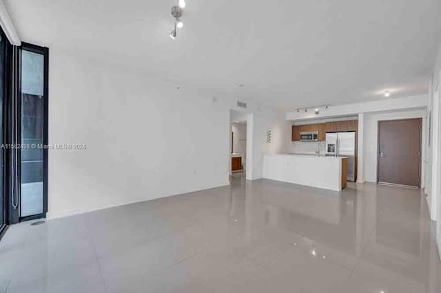 unfurnished living room featuring track lighting and light tile floors