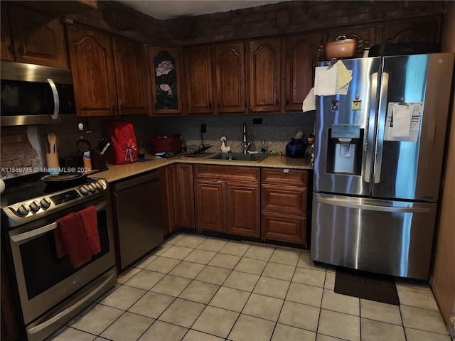 kitchen featuring stainless steel appliances, light tile flooring, tasteful backsplash, and sink