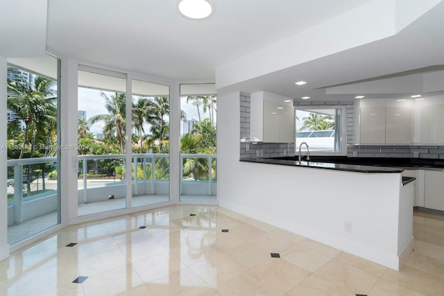 kitchen featuring floor to ceiling windows, white cabinets, sink, and light tile flooring