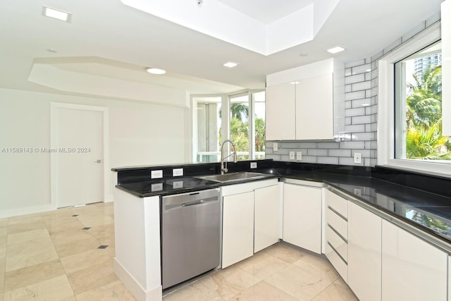 kitchen featuring stainless steel dishwasher, a tray ceiling, white cabinets, sink, and light tile flooring